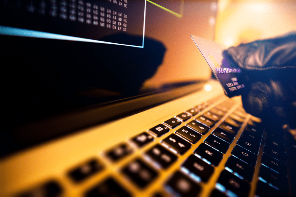 Mãos digitando em um notebook iluminado, representando fraude bancária online