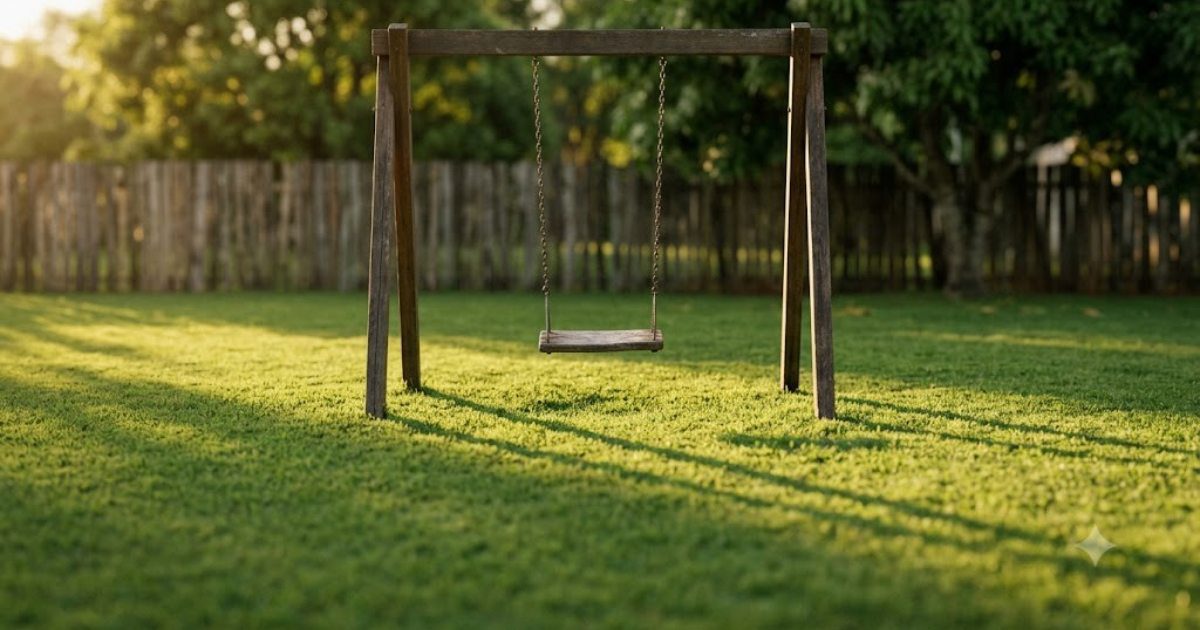 Balanco de playground vazio no quintal, grama verde, luz de fim de tarde