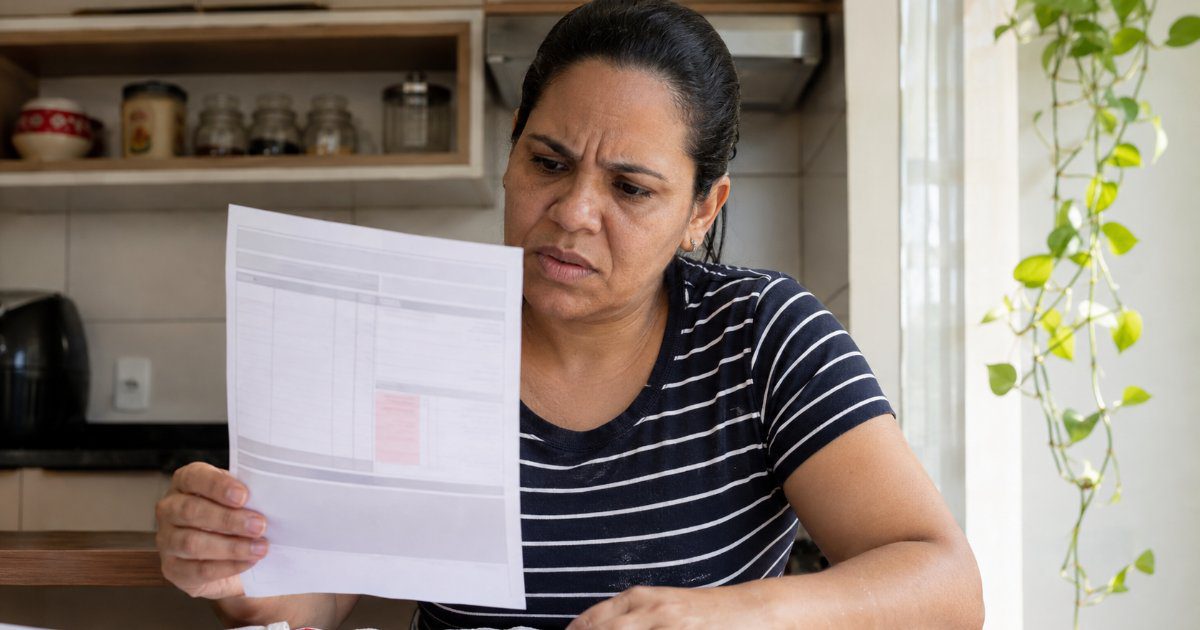 Mulher indignada olhando contracheque com desconto indevido do salário, cena editorial