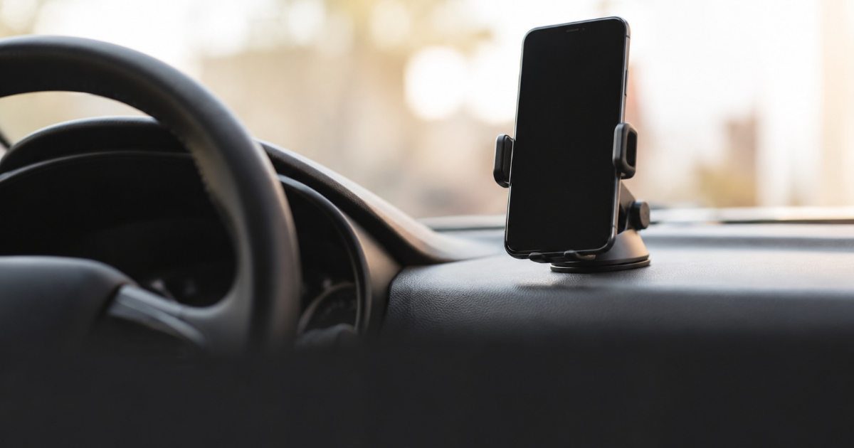 smartphone apoiado no suporte do painel de um carro com tela apagada