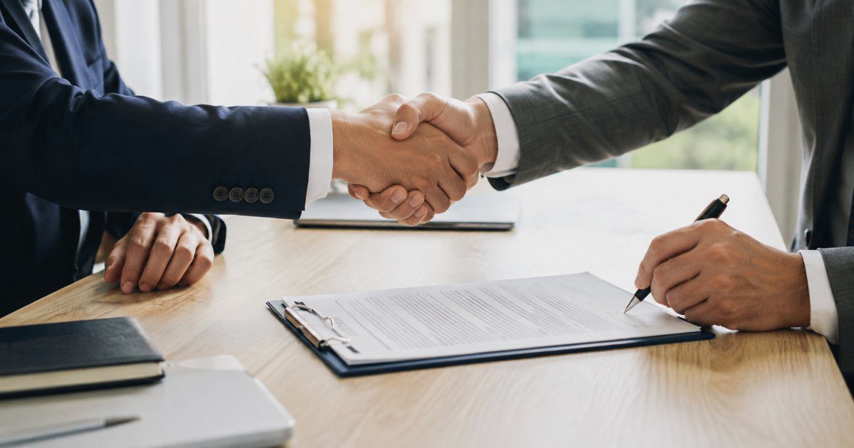 Aperto de mãos sobre um contrato de prestação de serviços em mesa de escritório