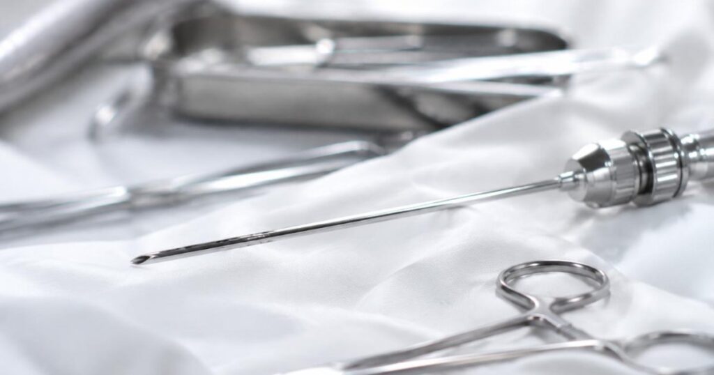 Canula de lipoaspiracao e instrumentos cirurgicos sobre campo esteril branco