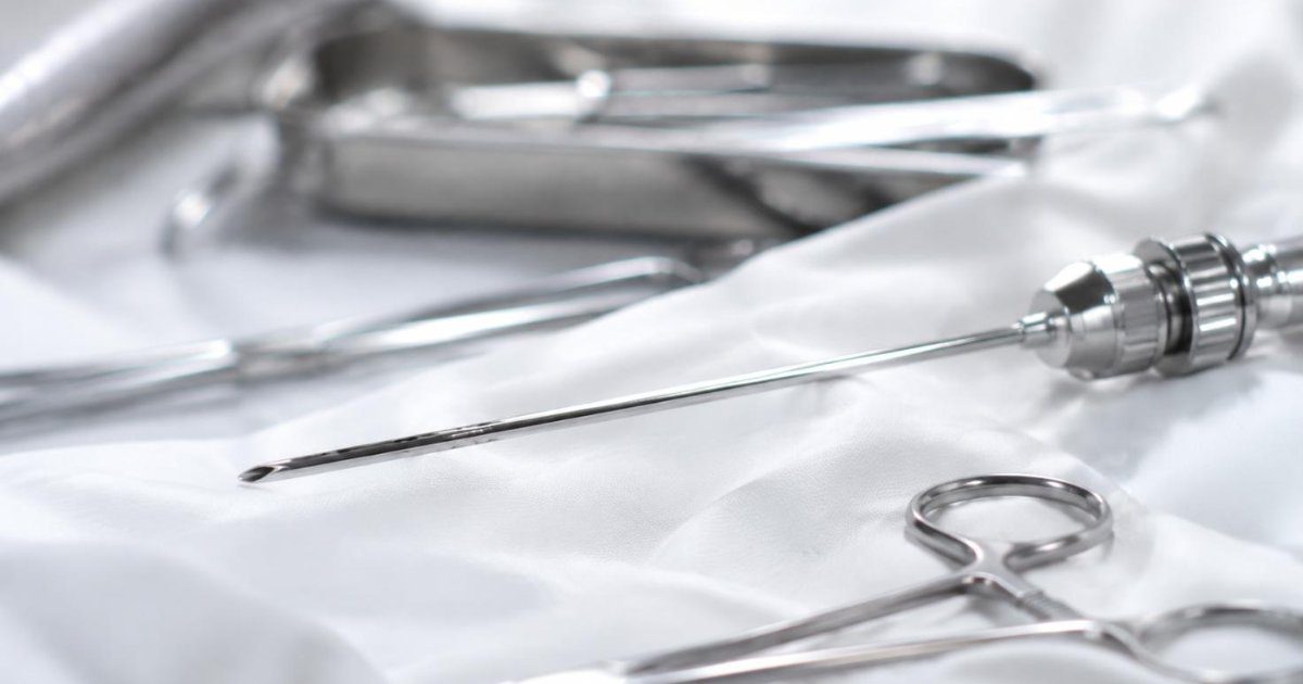 Canula de lipoaspiracao e instrumentos cirurgicos sobre campo esteril branco