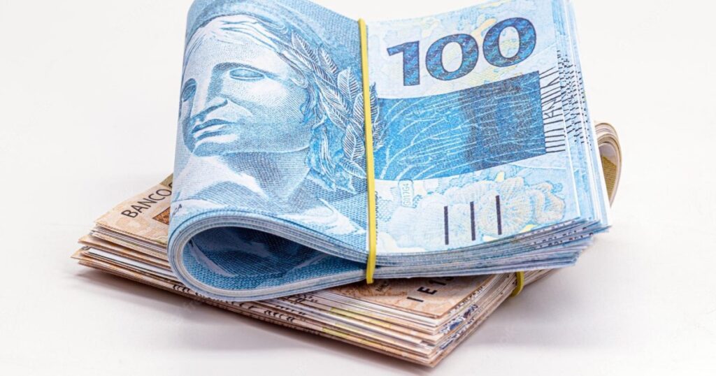 Maço de notas de cem reais representando valores a recuperar após golpe bancário