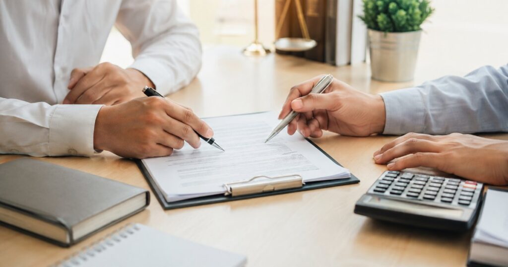 Revisão de cláusulas de contrato com caneta e calculadora em mesa de escritório