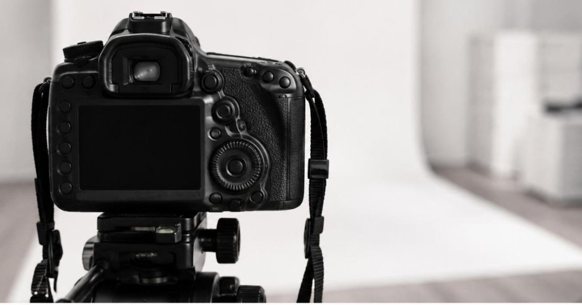 Camera fotografica em tripe apontada para fundo branco de estudio clinico